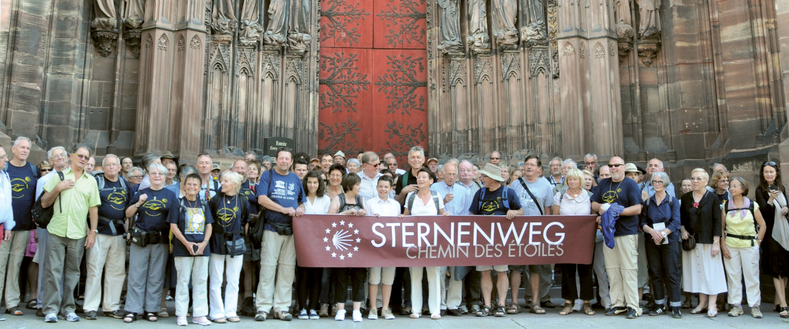 Menschengruppe vor Dom mit Sternenweg Banner