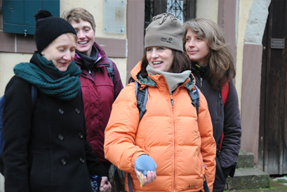 Eine Gruppe junger Frauen in Winterkleidung vor einer Hauswand